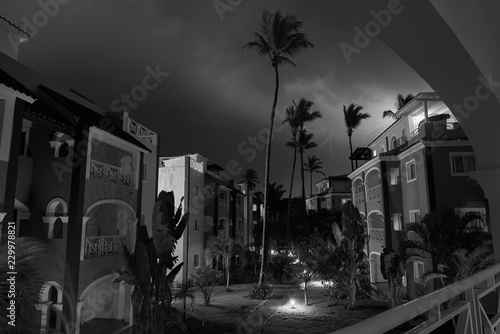 Monocrome long exposure shot of residence in small town Bavaro. Shot made in stormy night with heavy cloudy sky and lightnings in it. Path through te residence is lighten with small lanterns. photo