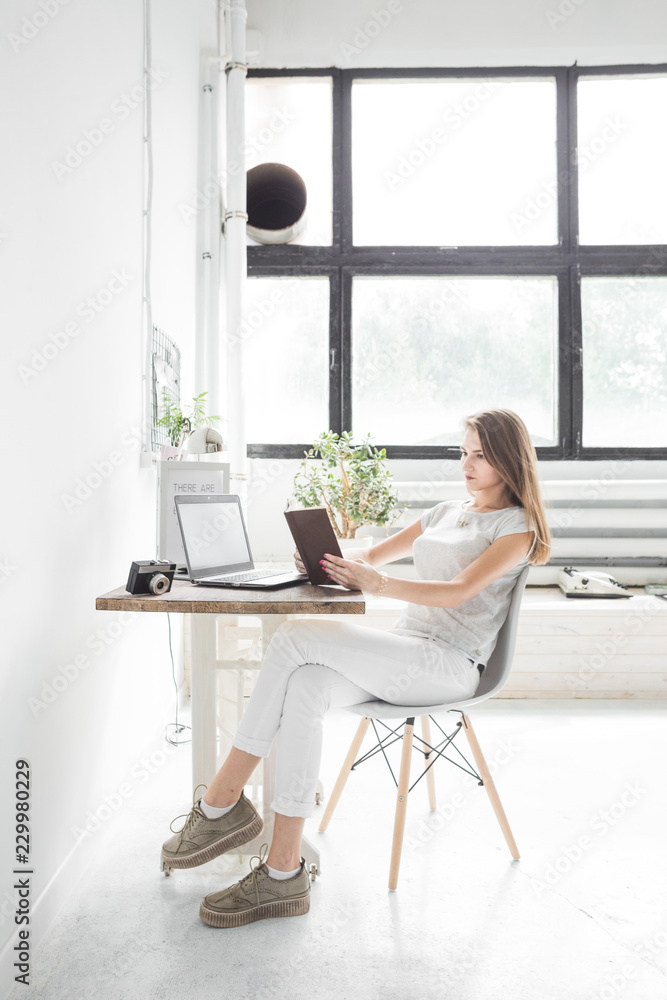 Young business woman working at home and reading a book. Creative Scandinavian style workspace Young business woman working at home and reading a book. Creative Scandinavian style workspace