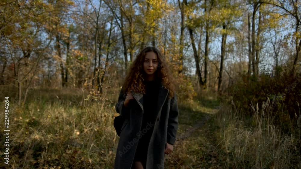 Young woman slowly walking in autumn park, shallow depth of field, slow motion Young woman slowly walking in autumn park, shallow depth of field, slow motion