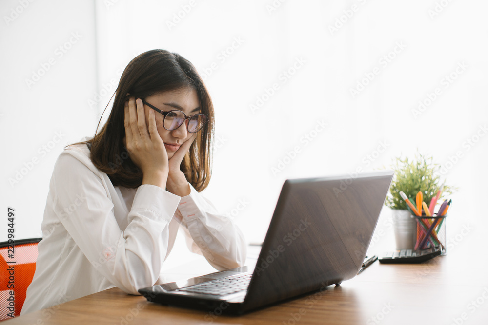Sad tired woman having a bad headache, she is sitting at office desk and touching her temple Sad tired woman having a bad headache, she is sitting at office desk and touching her temple