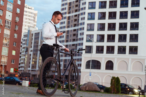 Fototapeta Naklejka Na Ścianę i Meble -  Handsome businessman with bike using a smart phone