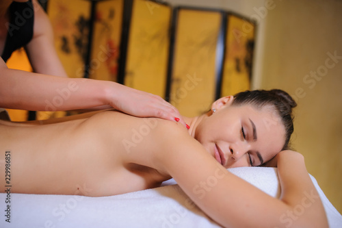 Masseur making massage on the upper back of a woman in spa
