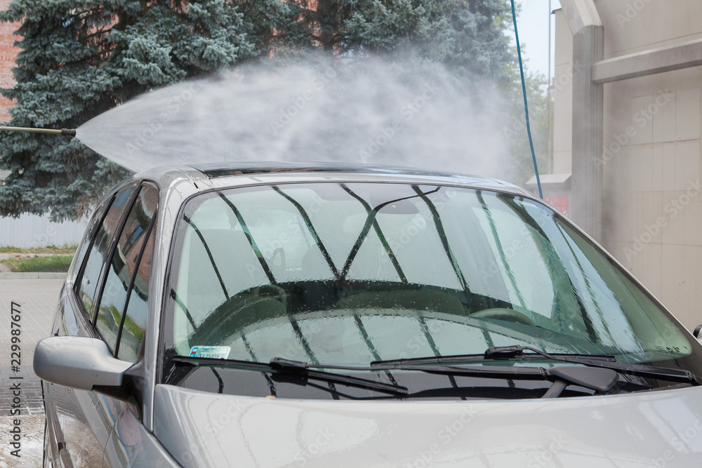 Obraz premium Summer Car Washing. Cleaning Car Using High Pressure Water