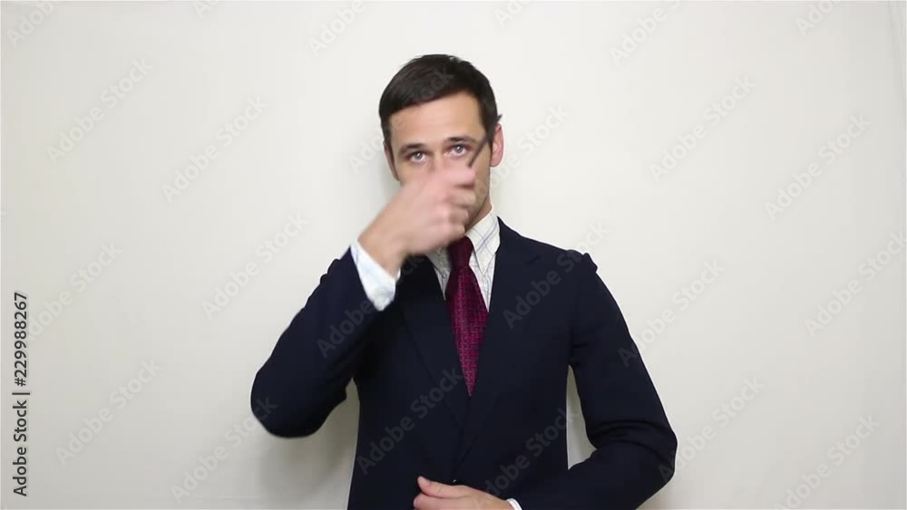 Young handsome businessman in a blue suit combing her hair looking at the camera.Portrait on a white background. Young handsome businessman in a blue suit combing her hair looking at the camera.Portrait on a white background.