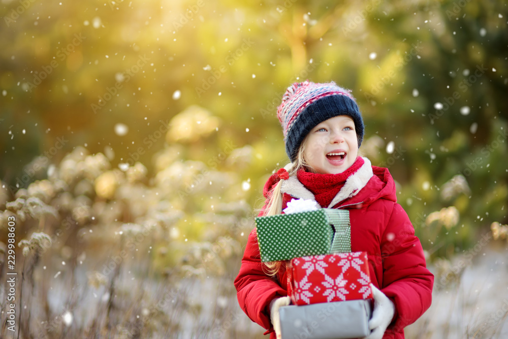 Adorable little girl holding a pile of Christmas gifts on beautiful sunny winter day. Adorable little girl holding a pile of Christmas gifts on beautiful sunny winter day.