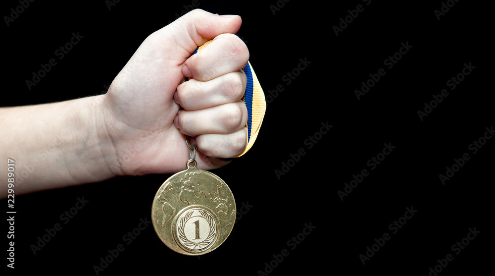 Fototapeta premium Woman hand holding gold medal against black background. Award and victory concept