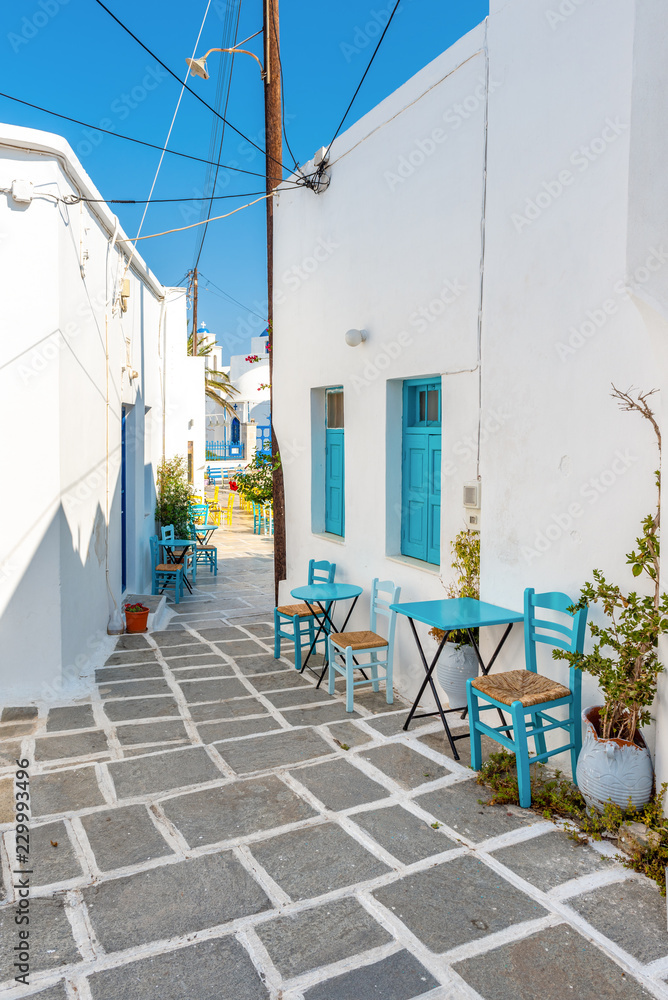 Fototapeta premium Paved alley with tables and chairs in Chora. Serifos island, Greece