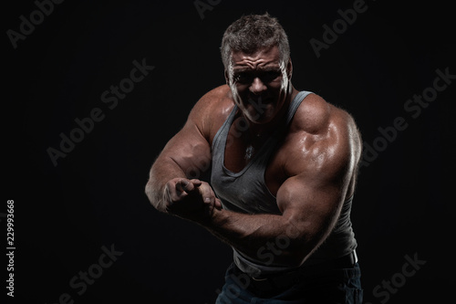 Wallpaper Mural powerful muscular man shows biceps on a black background. Strength and fitness concept Torontodigital.ca