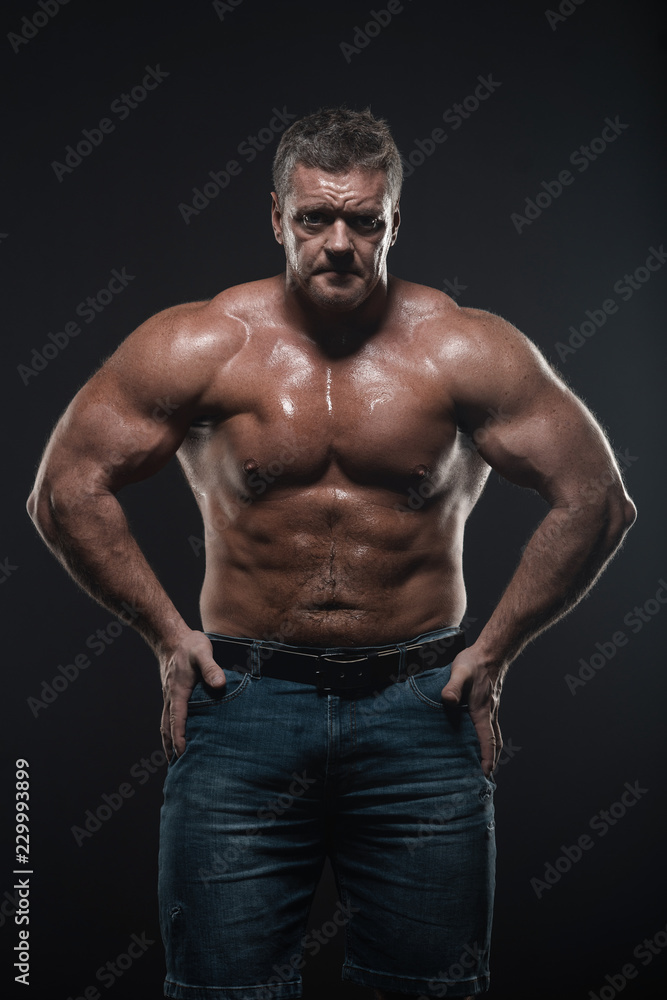 Powerful muscular bodybuilder posing on a black background. concept of strength and health Powerful muscular bodybuilder posing on a black background. concept of strength and health