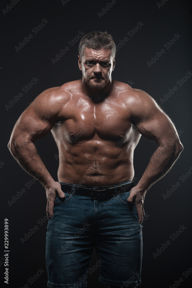 Powerful muscular bodybuilder posing on a black background. concept of strength and health