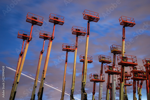 Group of cherry pickers at dusk with a plane passing