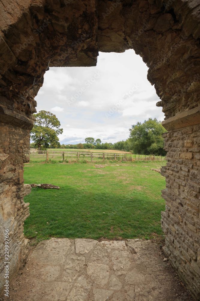 Ancient archway in ruins looking out onto English countryside on sunny day