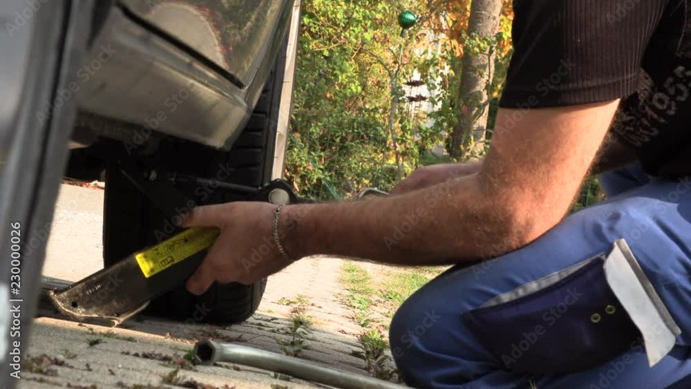 A man in work trousers replaces a car wheel,Slow Motion A man in work trousers replaces a car wheel,Slow Motion