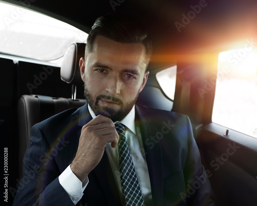 businessman with laptop sitting in a comfortable car