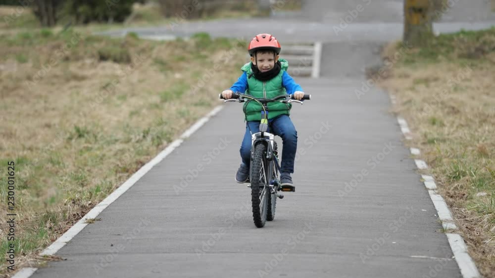 Little boy riding bicycle on alley, kid with protection helmet learning Little boy riding bicycle on alley, kid with protection helmet learning