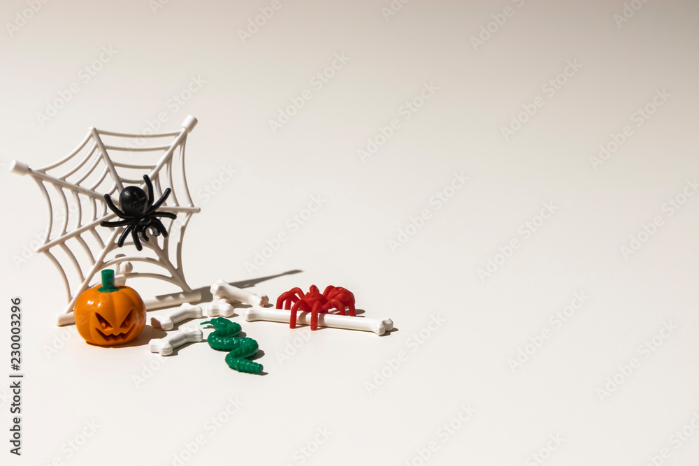 Composition of plastic toys for Halloween, with pumpkin, spider, cobweb, snake and bones