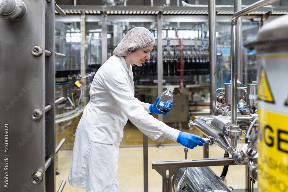 Worker at bottling factory checking juice quality. Worker at bottling factory checking juice quality.