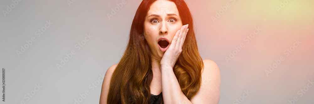 Emotional plus size model standing in studio with open mouth screaming showing despair on gray background Emotional plus size model standing in studio with open mouth screaming showing despair on gray background