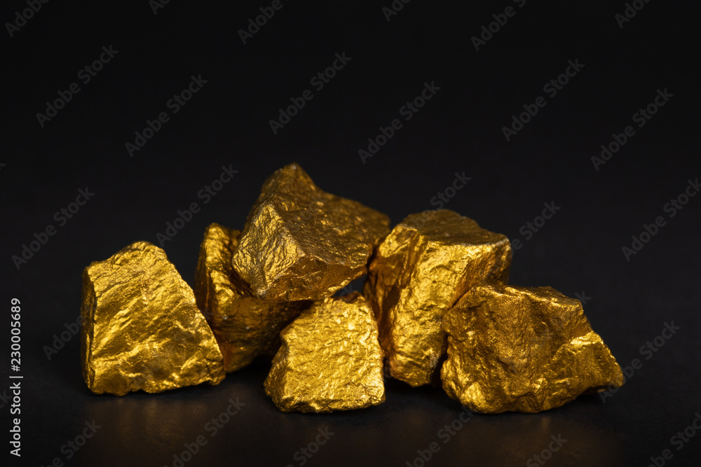A pile of gold nuggets or gold ore on black background, precious stone or lump of golden stone, financial and business concept. A pile of gold nuggets or gold ore on black background, precious stone or lump of golden stone, financial and business concept.
