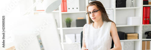 Beautiful Young Girl Sits at Desk in Office and Typing Text on Keyboard.