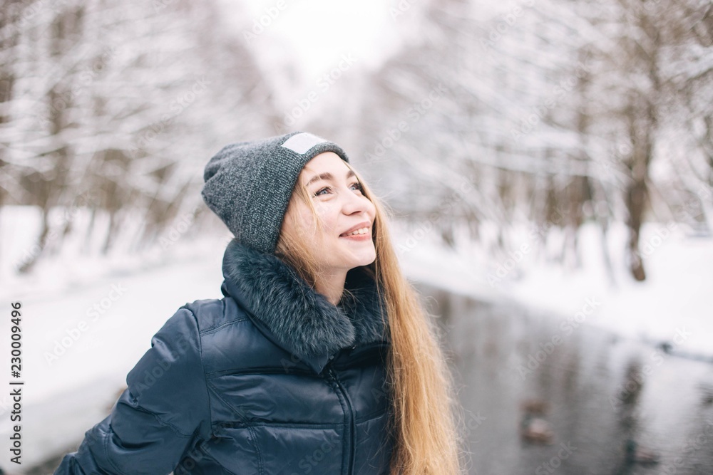beautiful girl in the woods in winter in winter clothes in the frost. place for a logo on the cap.