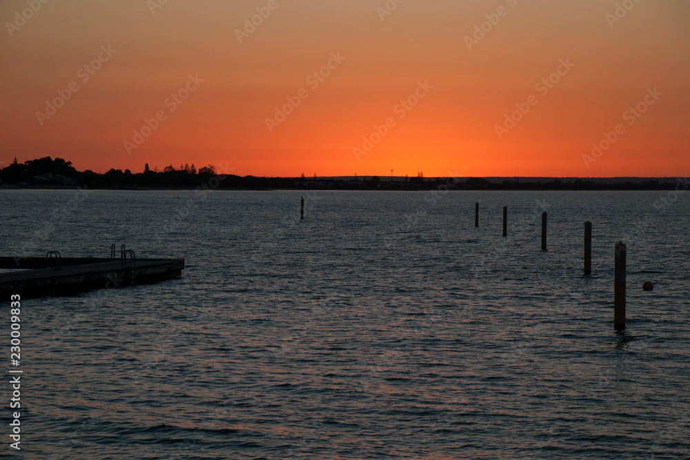 Busselton Australia, Orange sunset over Geographe Bay with ocean bathes in foreground