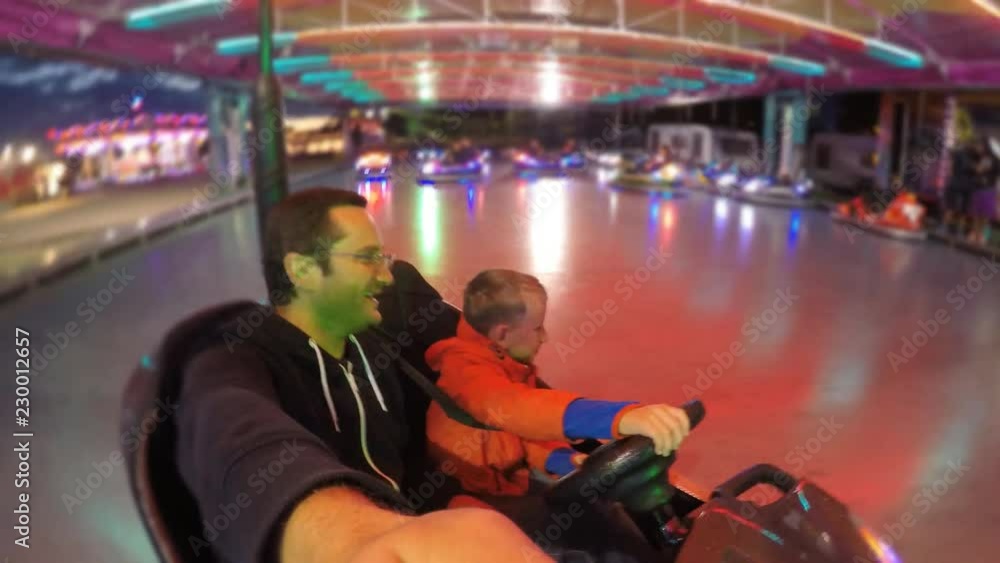 Confident child is driving at roller coaster, father have fun with son Confident child is driving at roller coaster, father have fun with son
