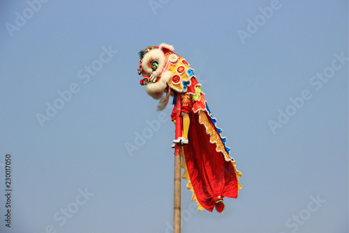 Chinese lion dance on the pole with the background of clear blue sky.