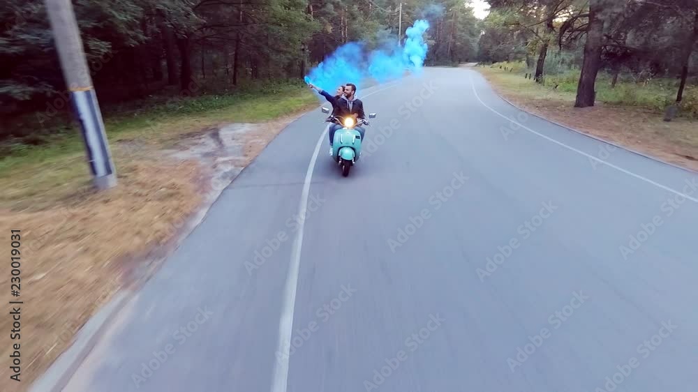 Couple riding a scooter. The girl in the hands holding the flare. Slow motion. Couple riding a scooter. The girl in the hands holding the flare. Slow motion.