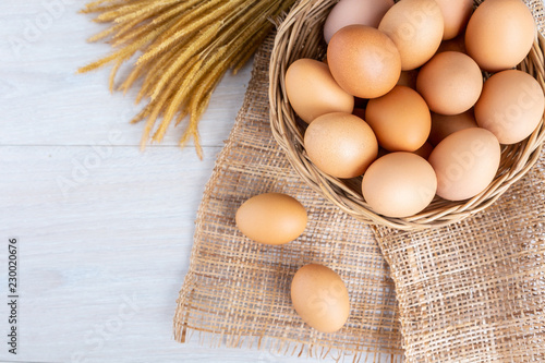 Eggs in a wooden basket on a white wooden table.