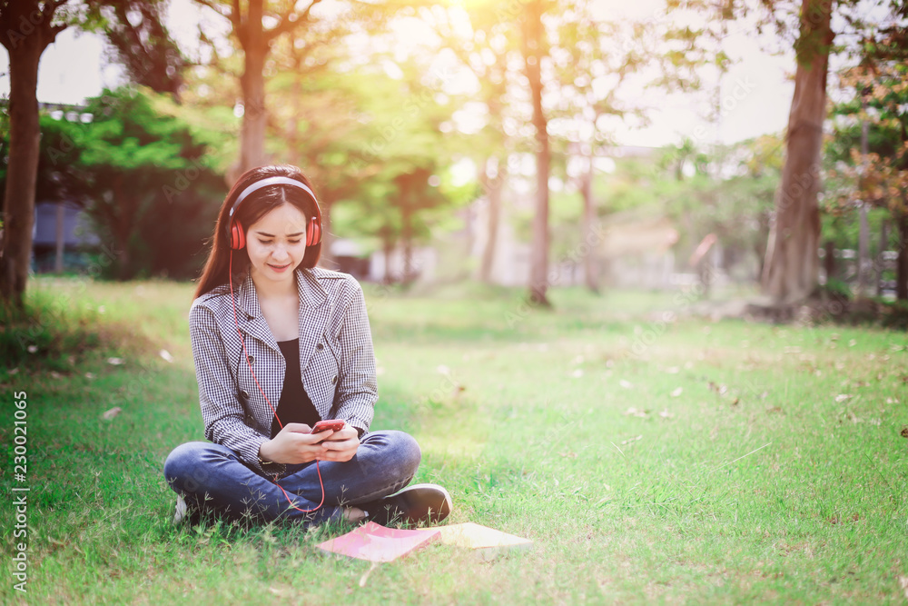 Education concept - Asian student or college woman reading a book on the green grass in the park happily and relax, She has a bright and beautiful smile. Education concept - Asian student or college woman reading a book on the green grass in the park happily and relax, She has a bright and beautiful smile.