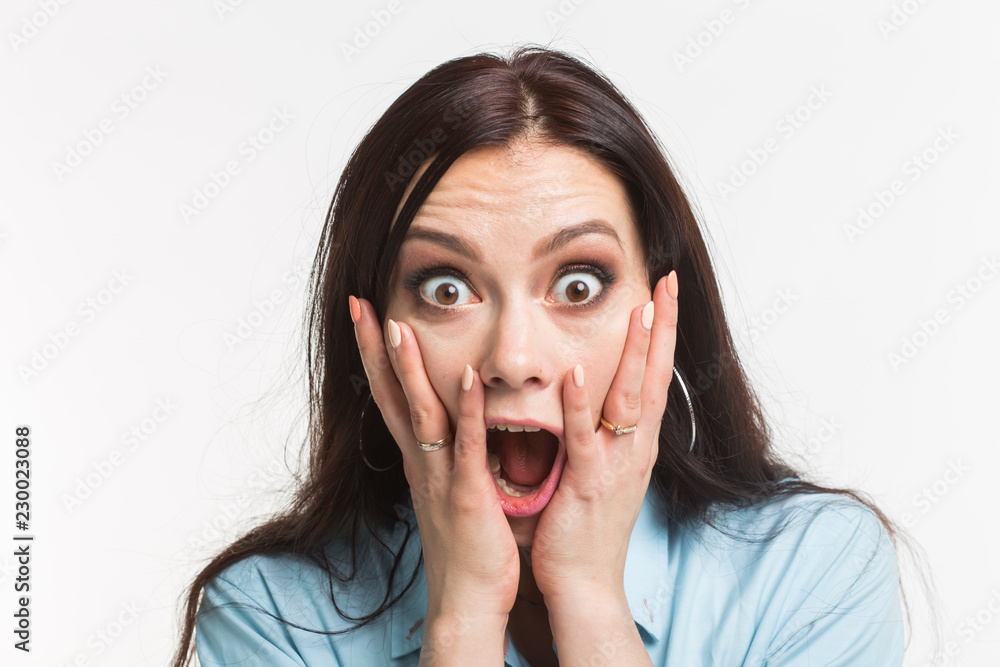 Emotions and people concept - young woman surprised, scared and close her mouth by hands on white background Emotions and people concept - young woman surprised, scared and close her mouth by hands on white background