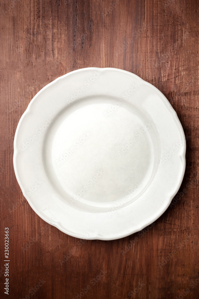 White plate, shot from the top on a dark rustic wooden background with copy space White plate, shot from the top on a dark rustic wooden background with copy space