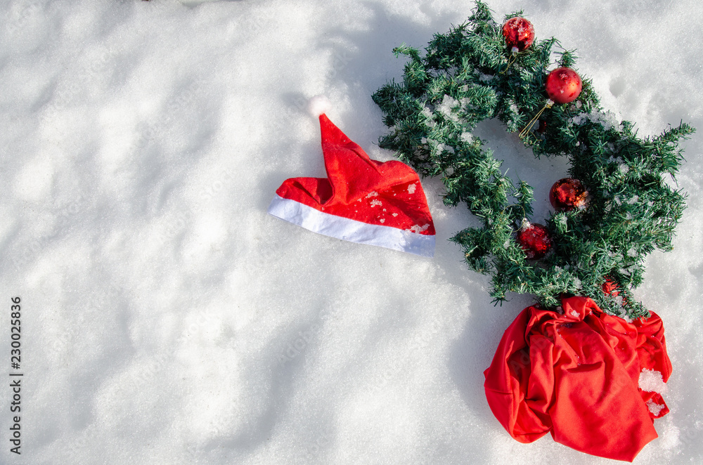 Traditional Christmas symbols on the snow. Santa's bag and hat, Christmas wreath and decorations for the Christmas tree