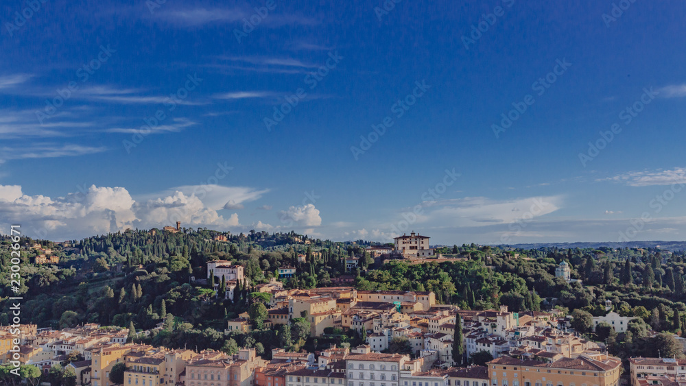 Renaissance houses on hill under blue sky in Florence, Italy