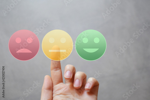 Finger rating with neutral happy sad face icons by pressing yellow button on virtual interface. Customer satisfaction service quality online evaluation and survey. Neutral feedback concept. photo