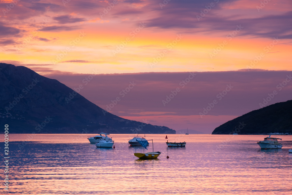 View from the city of Budva on the island of St. Nicholas. Sunrise at the sea. Sea, mountains, island and boats. Montenegro