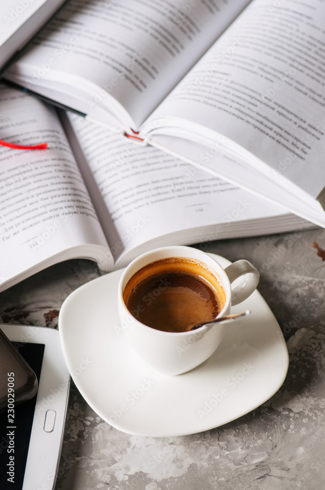 Group of opened books, cup of coffee, tablet and smartphone on a gray background, Overhead view. Group of opened books, cup of coffee, tablet and smartphone on a gray background, Overhead view.