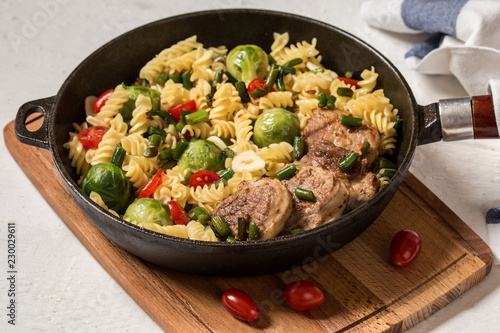 Pasta with vegetables and meat on a cutting Board on a light background