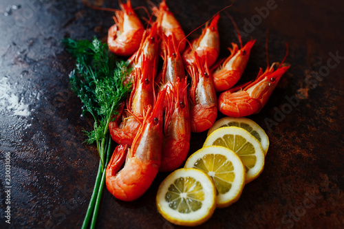 shrimp large pink whole with head and paws and tail against the background of slices of lemon and dill close-up of beer snack