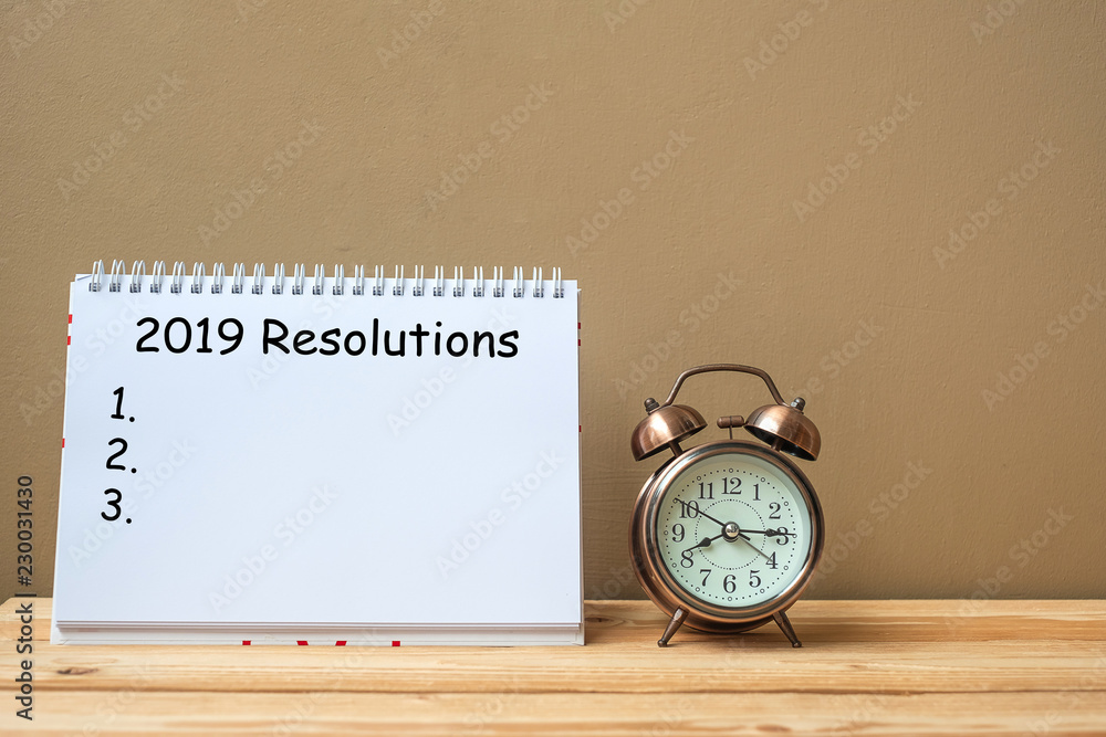 2019 Resolutions text on notebook and retro alarm clock on table and copy space. Goals, Mission and New Start Concept 2019 Resolutions text on notebook and retro alarm clock on table and copy space. Goals, Mission and New Start Concept