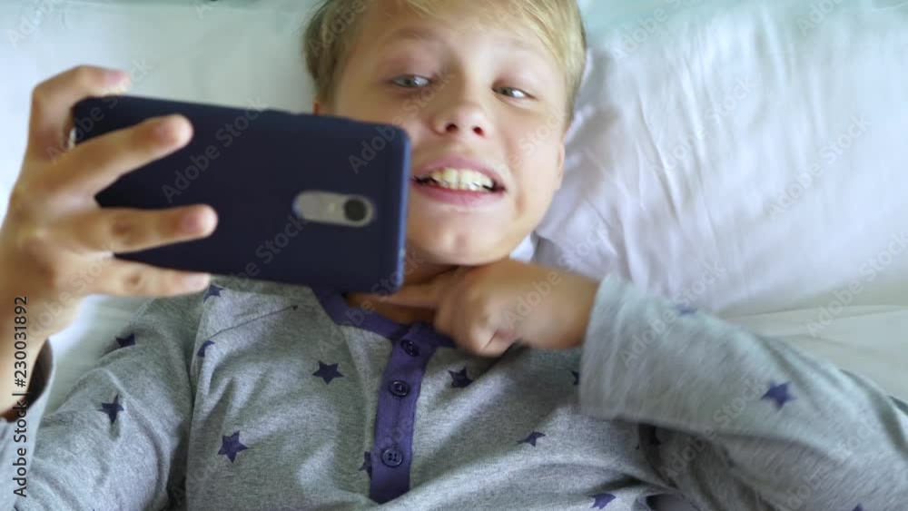 Funny little kid making video call using modern mobile telephone. Boy cheerfully making gesture of cutting head off. Real time 4k video footage. Funny little kid making video call using modern mobile telephone. Boy cheerfully making gesture of cutting head off. Real time 4k video footage.