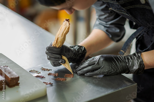 Tableau sur toile Pastry chef making chocolate cream sweets, wearing black gloves