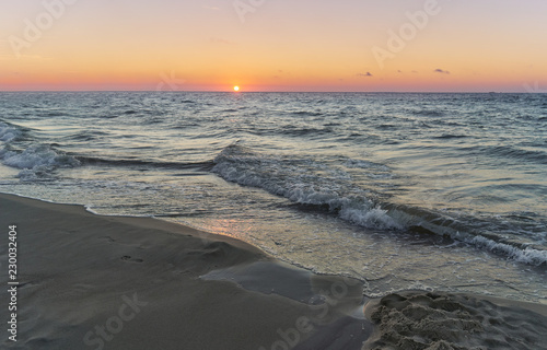 Sunset on Baltic Sea white pastel color sky and rough sea. 