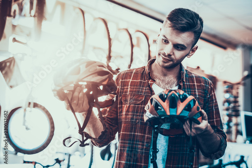 Guy Looks Closely at Helmets for Bicycle Rides. © VadimGuzhva