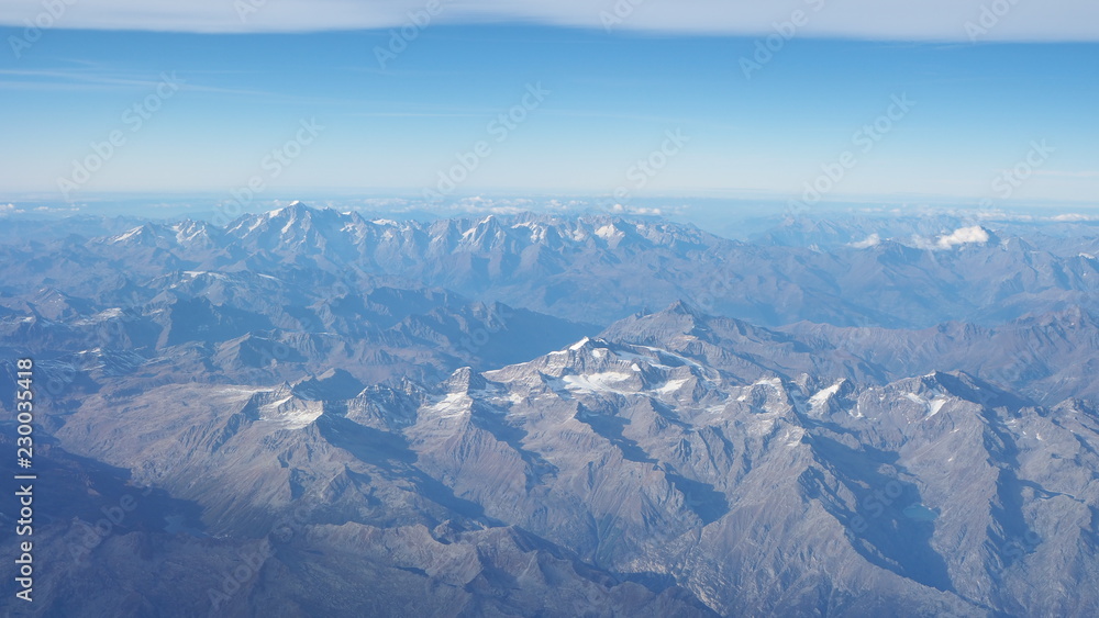 Fototapeta premium Flying over the European Alps during fall season. Landscape at the Mont Blanc and the glaciers. Aerial view from the airplane window