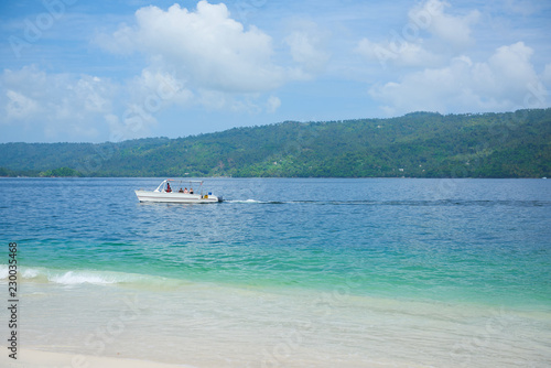 tourist boat floating in the waters of Samana Bay near the island Cayo Levantado. Boat is white. sky and water are blue. Cayo Levantado, also known as Bacardi Island, is an islet in Samana Bay © dmitry_zubarev