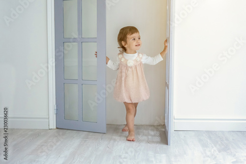 Little cute sweet smiling girl in pastel pink dress dancing in bright light living room at home and laughing. Childhood, preschool, youth, relax concept