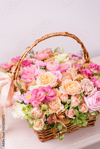 flowers arrangement with various of colors in wicker basket on pink table. beautiful spring bouquet. bright room  white wall. copy space