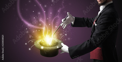 Magician hand conjure with wand  light from a black cylinder © ra2 studio